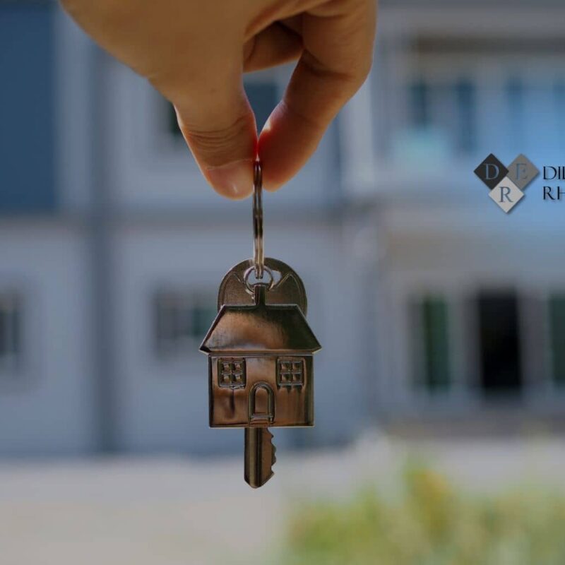 Hand holding a house-shaped key in front of a Florida home after a quiet title action cleared the property title, Dill, Evans & Rhodeback