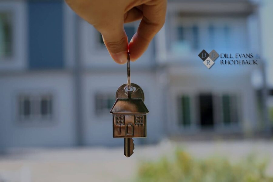Hand holding a house-shaped key in front of a Florida home after a quiet title action cleared the property title, Dill, Evans & Rhodeback